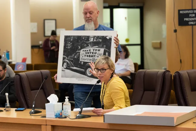 Paige Monlux (seated) and Terry Baxter of County Archives display an image from the County’s Elections record collection of a truck offering free transportation to voters circa April 1950.