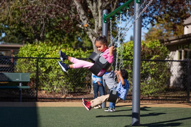 Preschoolers swinging on swingset at Menlo Park elementary school