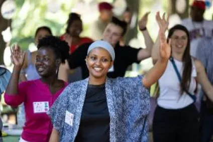 A group of women at a park celebration smile and wave