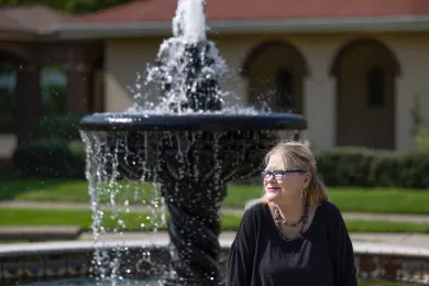 A woman sits in front of a fountain.