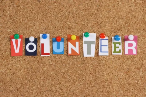 bulletin board with the word 'volunteer' with individual tacked-up letters
