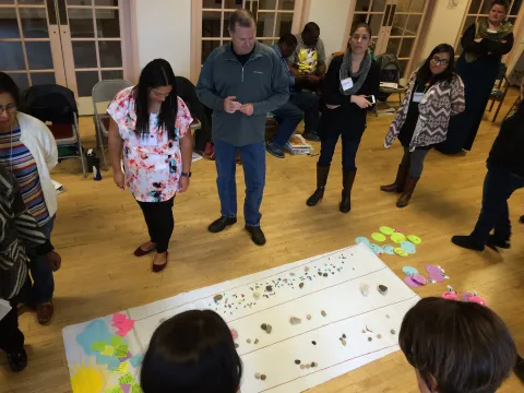 Community health workers gaze down at the results of a brainstorm at a training session.